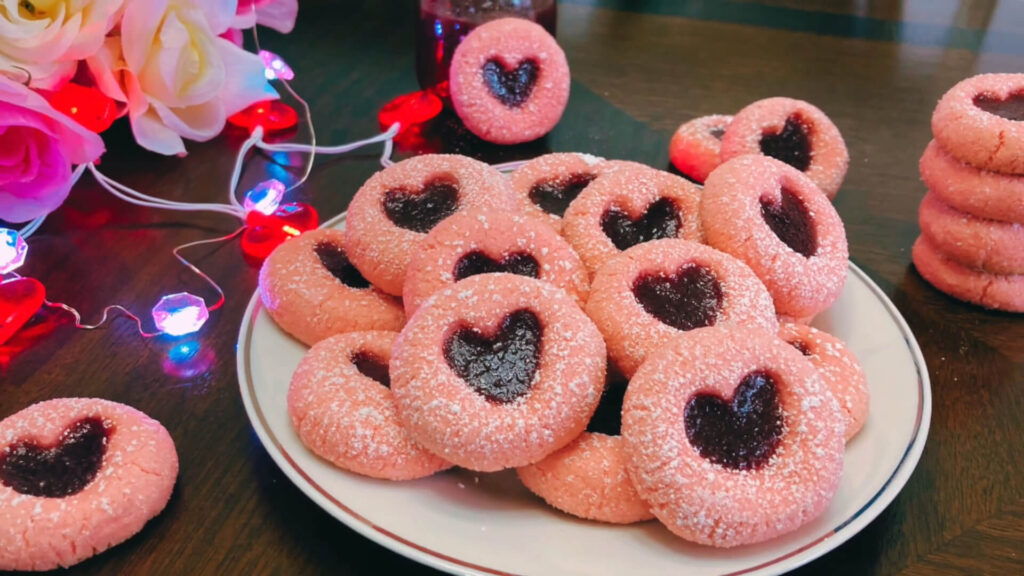 Decorated heart thumbprint cookies with chocolate drizzle and colorful sprinkles