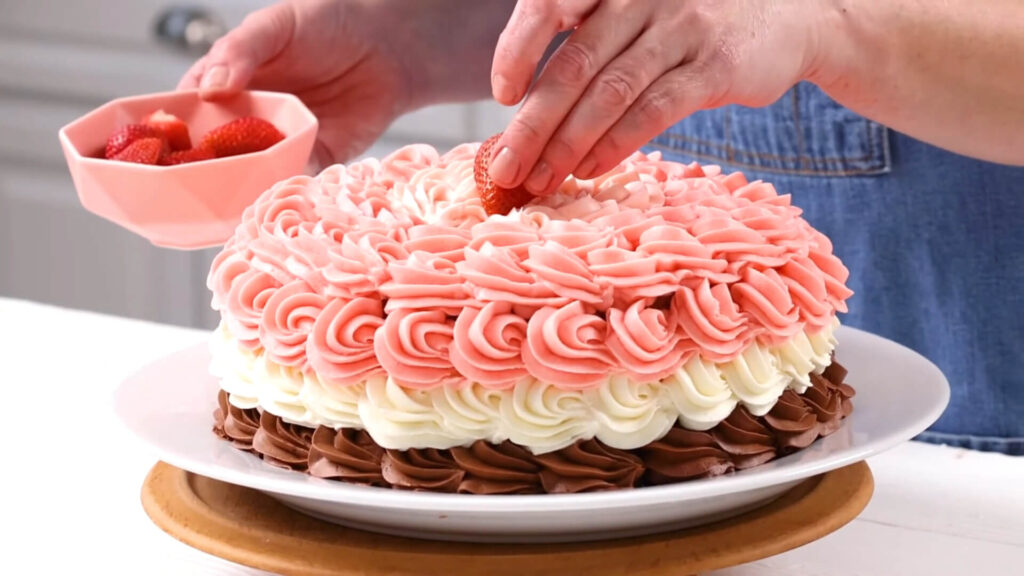 A well-decorated Neapolitan cake with layers of chocolate, vanilla, and strawberry, showcasing a smooth buttercream swirl design on top