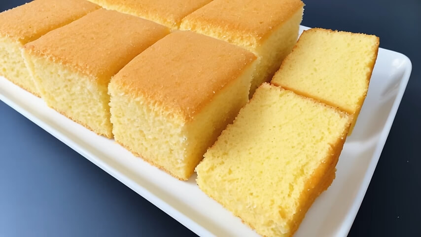 A beautifully baked vanilla cake, sliced to reveal its soft crumb